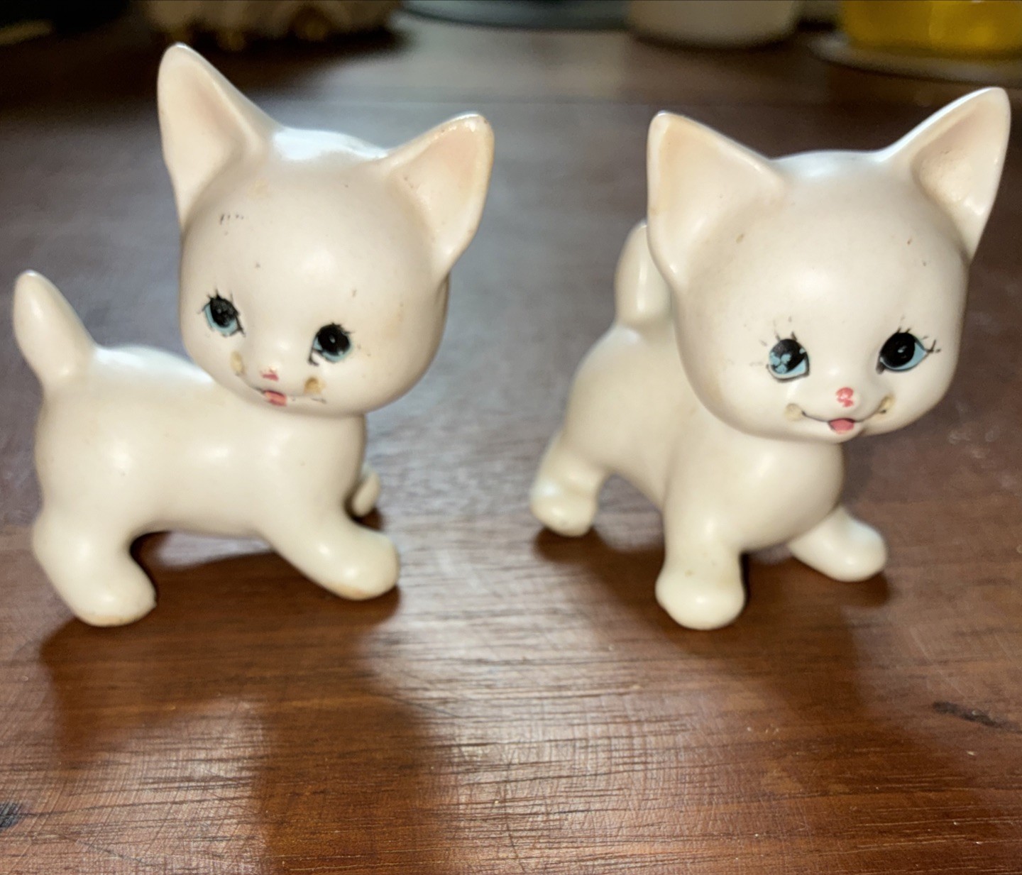 A pair of vintage, matte white ceramic cat figurines with painted details.