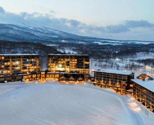 Park Hyatt Niseko Hotel illuminated with lights and blanketed in snow during the winter season.