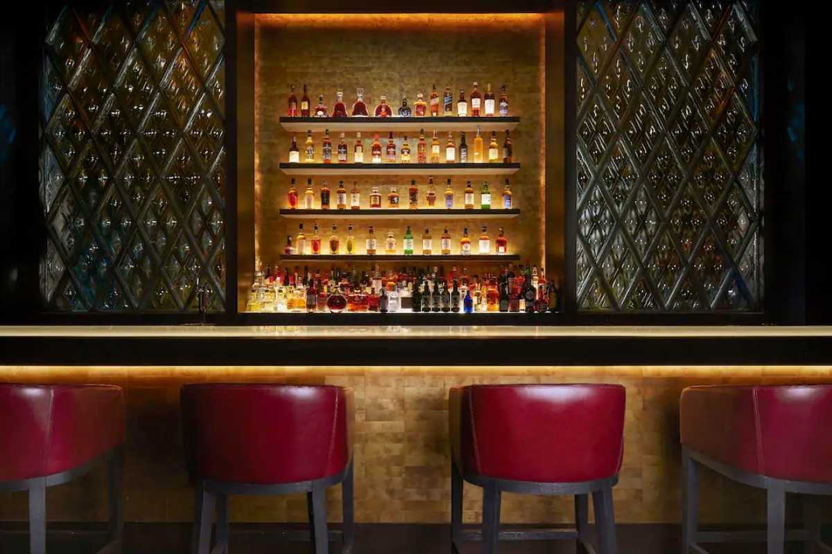 A stylish bar counter with stools, and bottles displayed neatly on shelves in Park Hyatt Niseko.