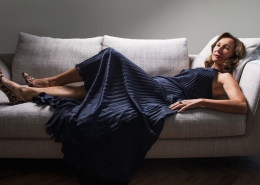 Claudia Hackman wearing a Versace navy dress lying on the couch.