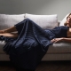 Claudia Hackman wearing a Versace navy dress lying on the couch.